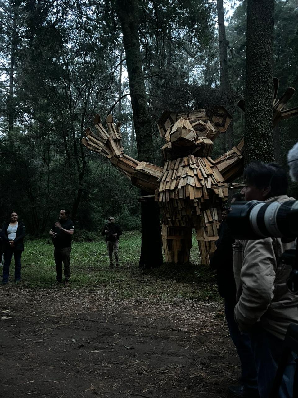 Participantes frente a una escultura de madera en el bosque